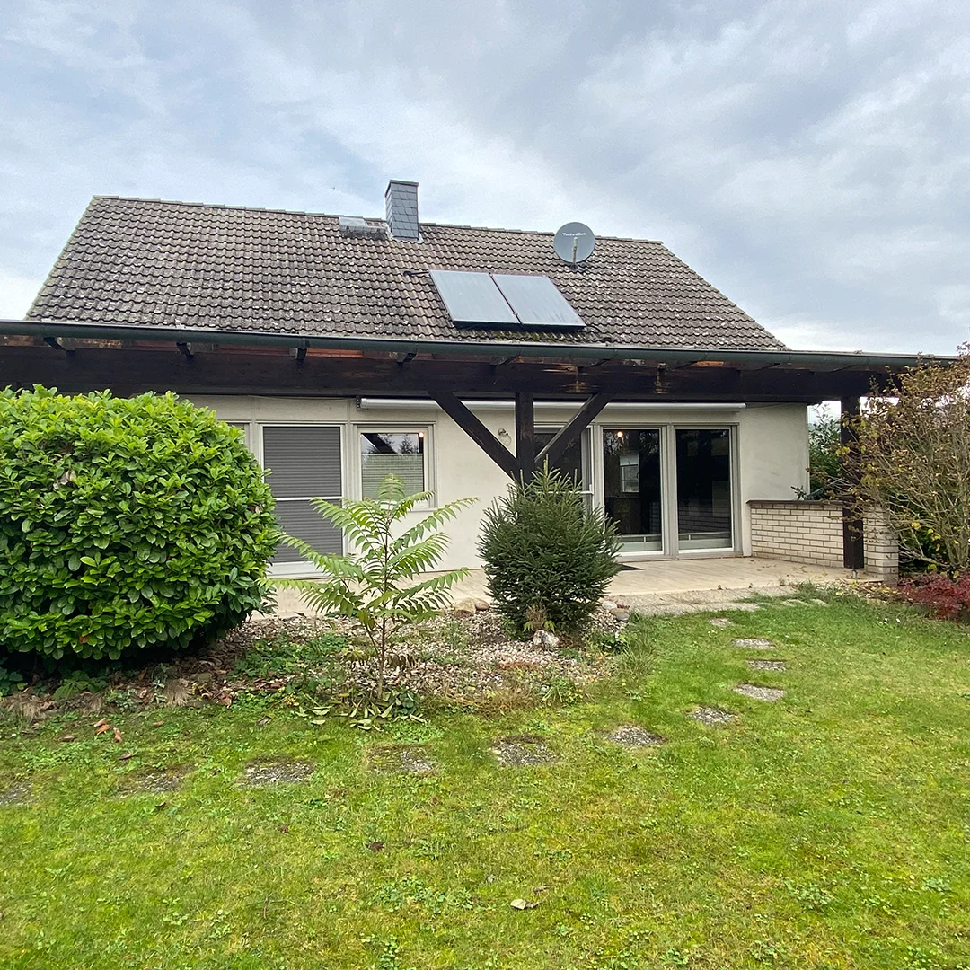 Einfamilienhaus Appenheim Ingelheimer Straße Außenbereich Einfamilienhaus mit Satteldach, Solarpanelen und Satellitenschüssel, davor Terrasse und gepflegter Garten mit Rasen und Sträuchern.
