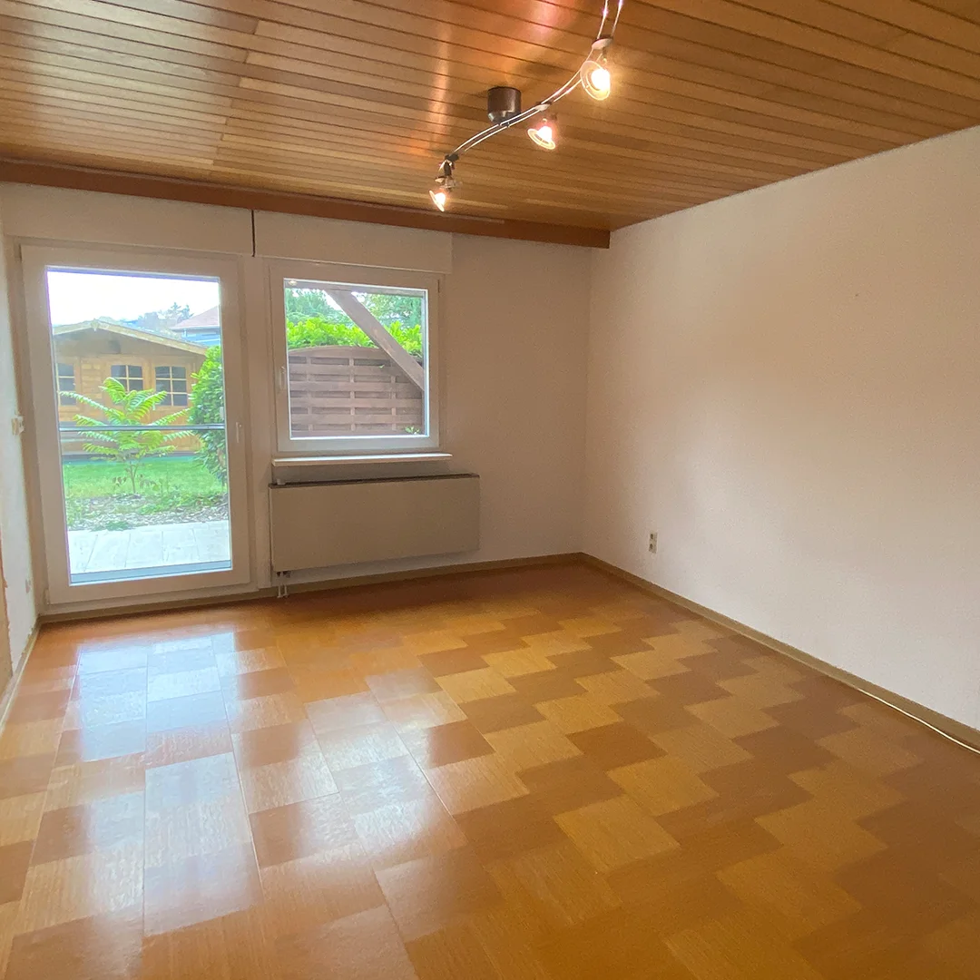 Einfamilienhaus Appenheim Ingelheimer Straße Schlafzimmer Leeres Schlafzimmer mit Holzboden, weiß gestrichenen Wänden, Holzdecke und großer Glastür zum Garten.