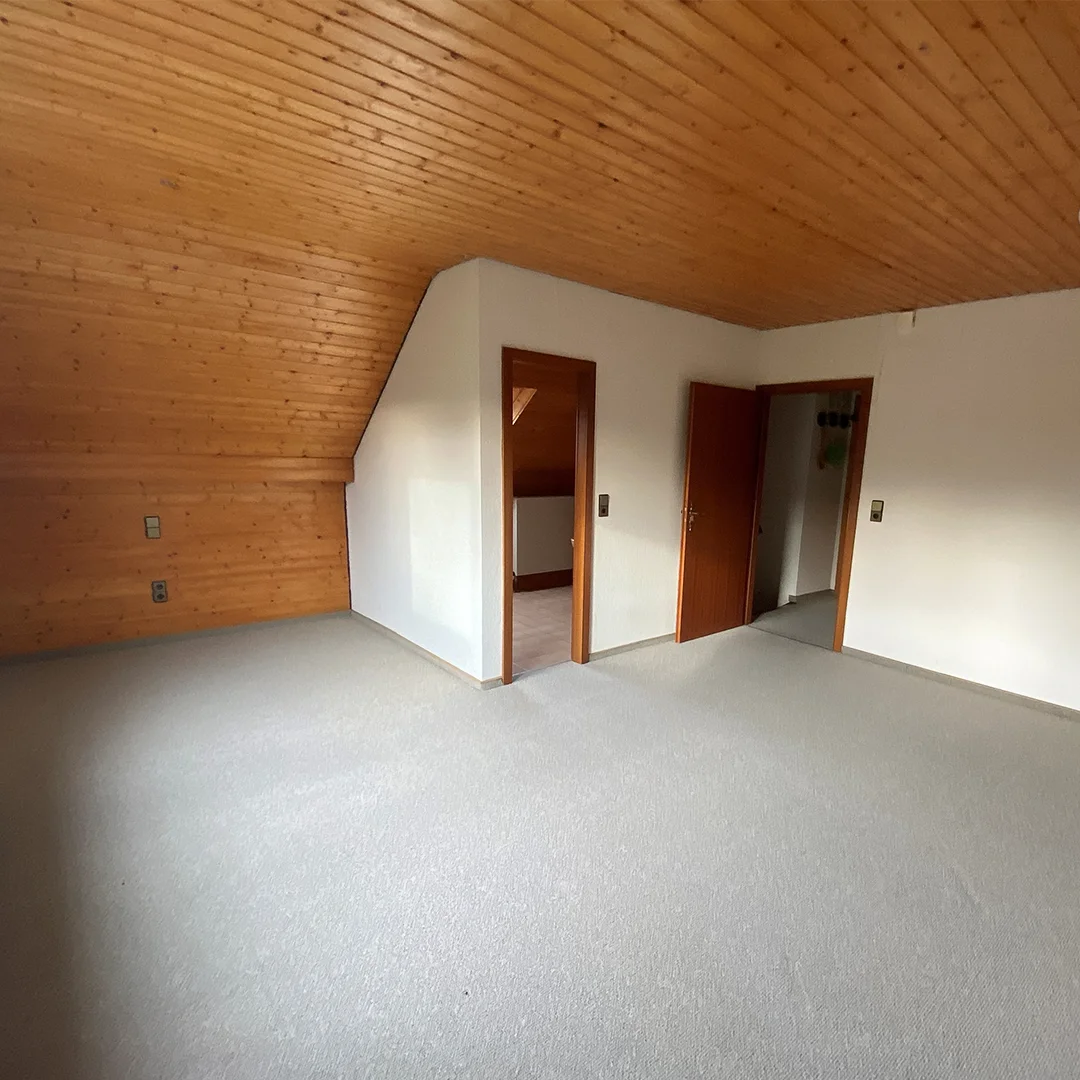 Einfamilienhaus Appenheim Ingelheimer Straße Studio Leeres Schlafzimmer mit Holzboden, weiß gestrichenen Wänden, Holzdecke und großer Glastür zum Garten.