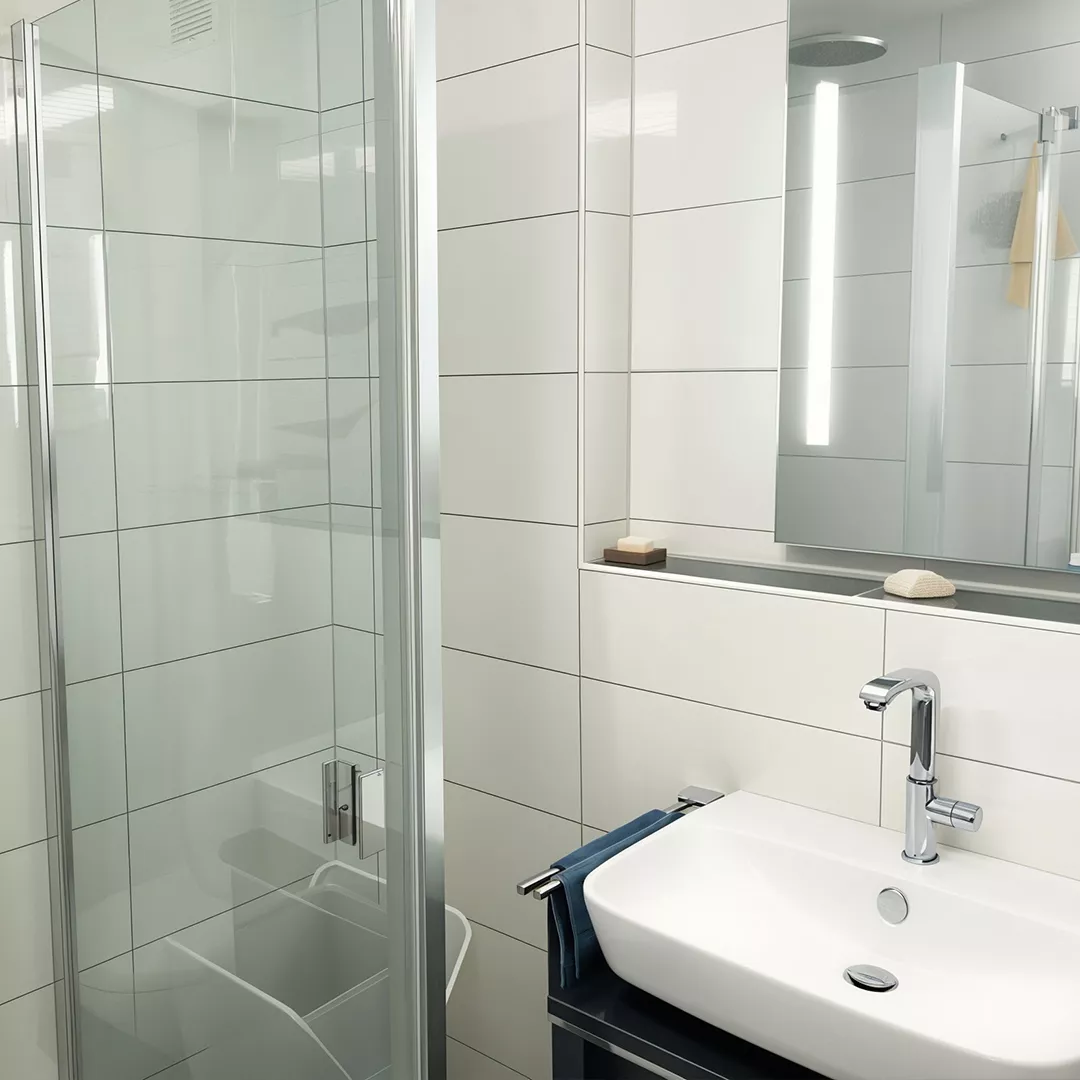 Modernes Badezimmer mit Glasdusche, rechteckigem Waschbecken auf schwarzem Unterschrank und beleuchtetem Spiegel.