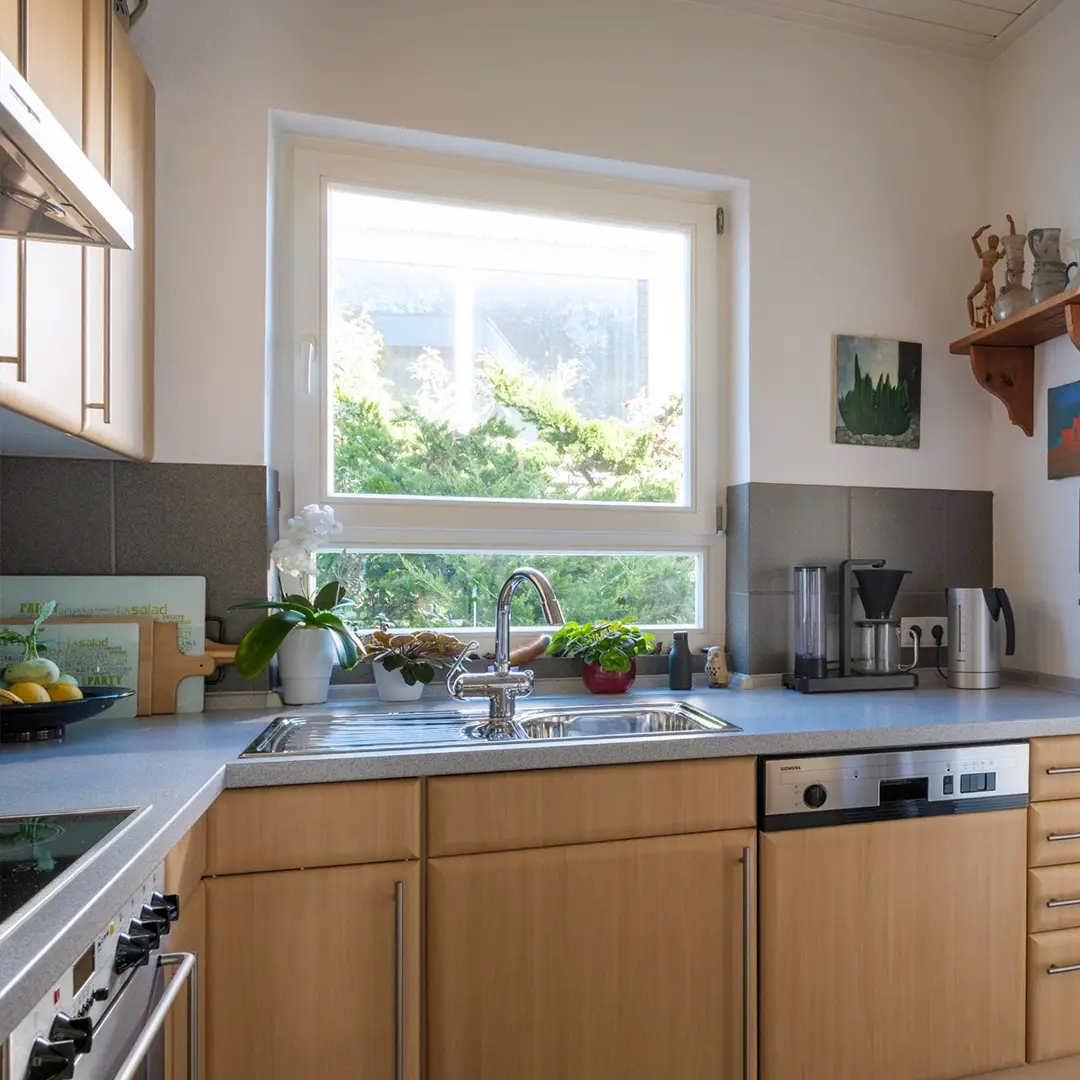 Küche mit braunen Holzfronten eines Einfamilienhauses in Wackernheim mit Küchenzeile, Einbaugeräten und großem Fenster